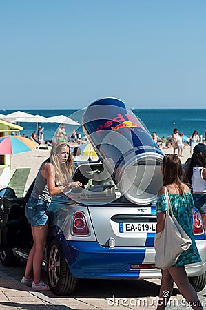 Portrait of sexy girls with jeans short and white teeshirt giving fresh red bull cans on the beach Editorial Stock Photo