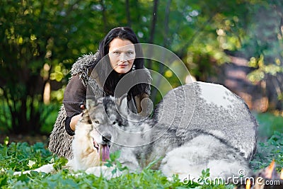 Shaman woman with an Alaskan Malamute dog next to the fire in the forest Stock Photo