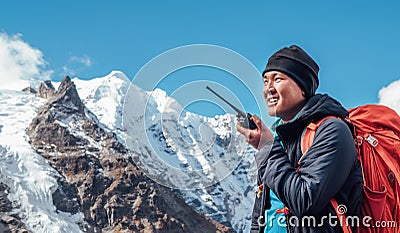 Portrait of Sherpa man with backpack using walkie-talkie for calling rescue helicopter with Mera peak 6476m background.High Stock Photo