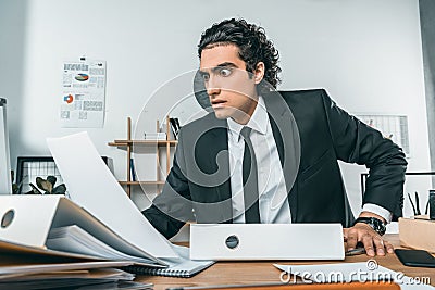 portrait of shocked businessman looking at documents at workplace Stock Photo