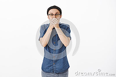 Portrait of shocked guy in stupor gasping trying not scream so covering mouth with palms staring shook and worried at Stock Photo