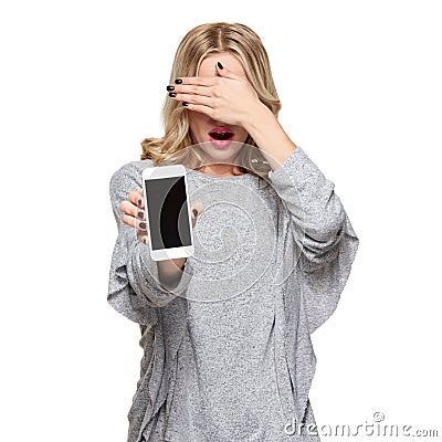 Portrait of shocked woman covering her eyes with hand showing mobile phone blank screen isolated over white. Shocking news. Stock Photo
