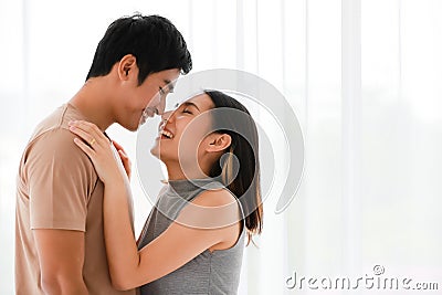 Portrait shot of cute smiling young Asian lover couple standing and passionate kissing together in the bedroom at weekends. Stock Photo