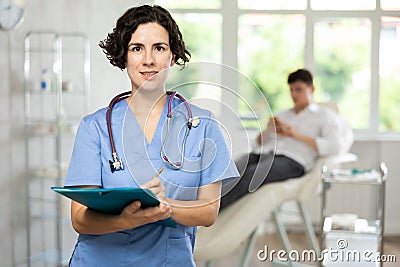 Portrait shot of female doctor holding clipboard in hand while standing in medical esthetic clinic Stock Photo