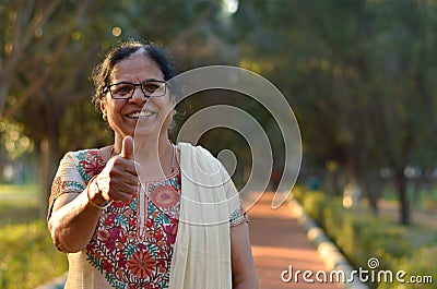 Portrait shot of a happy looking senior north Indian woman wearing traditional chikan kari Indian salwar kameez showing a thumbs Stock Photo