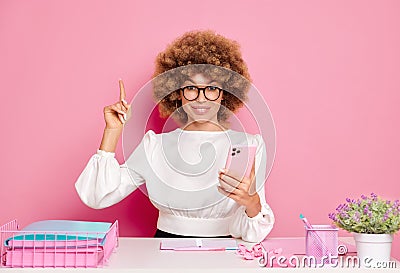 Portrait shot of office worker points index finger up, uses smartphone, shows copy space for your advertising, poses at Stock Photo