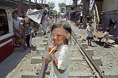 Portrait shy Filipino girl on railroad through slum Editorial Stock Photo