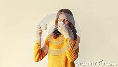 Portrait of sick upset woman sneezing blow nose using tissue and holding mug of hot coffee or drink Stock Photo