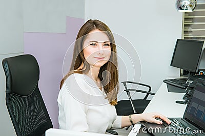 Portrait of skilled administrative manager working on laptop computer in office satisfied with occupation, young female receptioni Stock Photo