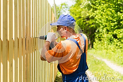 Portrait of skilled worker building wooden fence with cordless electric screwdriver Stock Photo