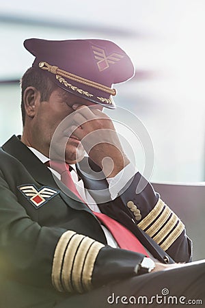 Portrait of sleepy and overworked pilot sitting in airport Stock Photo