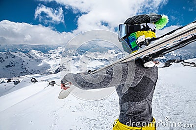 Portrait of a slender skier sportswoman in a cap, mask on her face and ski goggles, mask with skis on her shoulders Stock Photo