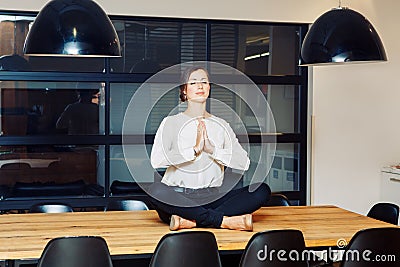 Portrait of slim fit sporty young white Caucasian business woman meditating doing yoga exercises Stock Photo