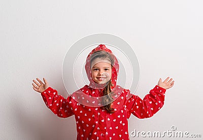 Portrait of a small girl with red anorak in studio on a white background. Stock Photo