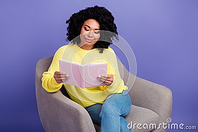 Portrait of smart clever erudite woman with afro hair wear knit sweater sit on armchair read book isolated on violet Stock Photo