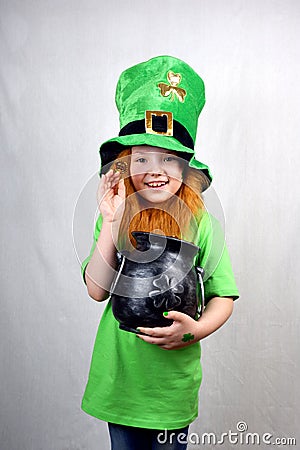 Portrait of smiling adorable girl with decorative red beard, green clover leaf on her cheek and leprechaun hat, dressed in green, Stock Photo