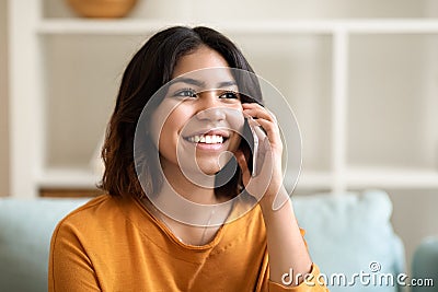 Portrait Of Smiling Arab Female Talking On Mobile Phone At Home Stock Photo