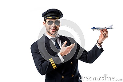 portrait of smiling bearded pilot in uniform pointing at toy plane in hand Stock Photo