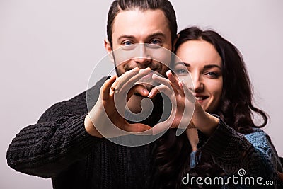 Portrait of smiling beauty girl and her handsome boyfriend making shape of heart by their hands. Stock Photo