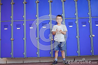 Portrait of smiling boy using mobile phone against lockers Editorial Stock Photo