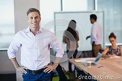 Portrait of smiling business executive standing with hands on hip in conference room Stock Photo