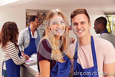 Portrait Of Smiling Couple Wearing Aprons Taking Part In Cookery Class In Kitchen Stock Photo