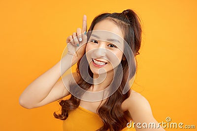 Portrait of a smiling cute woman making selfie photo on smartphone isolated on a yelllow background Stock Photo