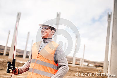 Portrait of smiling engineer on construction site, surveyor using gps system and theodolite on highway construction site Stock Photo