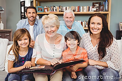 Portrait of smiling family with grandparents holding photo album Stock Photo
