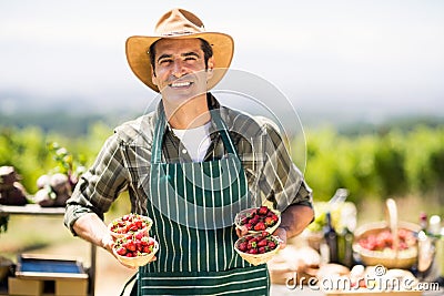 Portrait of a smiling farmer holding bowls of strawberries Stock Photo