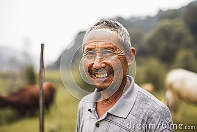 Portrait of smiling farmer with livestock in the background, rural China, Shanxi Province Stock Photo