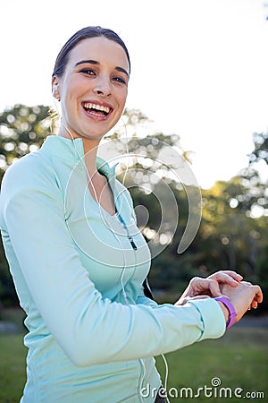 Portrait of smiling female jogger checking her fitness band Stock Photo