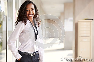 Portrait Of Smiling Female School Teacher Standing In Corridor Of College Building Stock Photo