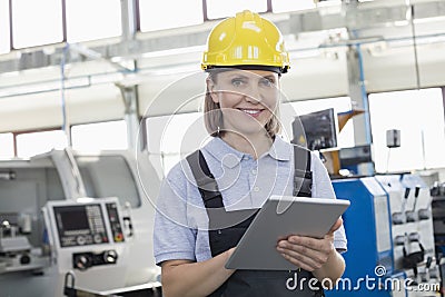 Portrait of smiling female worker using digital tablet in manufacturing industry Stock Photo