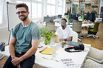 Portrait of smiling graphic designer sitting on his desk Stock Photo