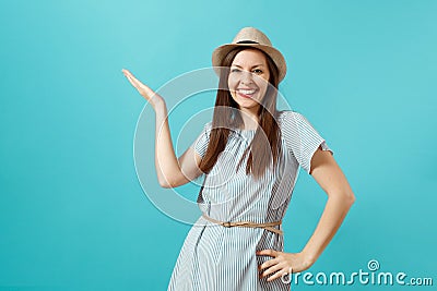 Portrait of smiling happy young elegant woman wearing dress, straw summer hat pointing hand aside on copy space isolated Stock Photo