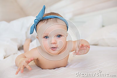 Portrait of smiling little infant with a blue diadem plays on a bed Stock Photo