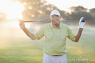 Portrait of smiling mature golfer carrying golf club Stock Photo