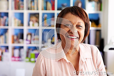 Portrait Of Smiling Mature Woman In Home Office By Bookcase Stock Photo