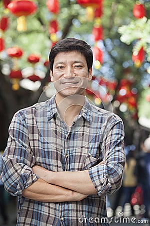 Portrait of Smiling Mid Adult Man with Arms Crossed in Nanluoguxiang, Beijing Stock Photo