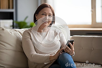 Portrait of smiling middle aged lady resting on sofa. Stock Photo