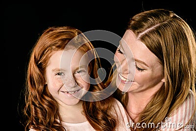 Portrait of smiling mother looking at adorable redhead daughter Stock Photo