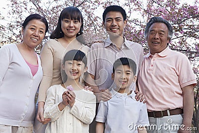 Portrait of a smiling multi-generational family amongst the cherry trees and enjoying the park in the springtime Stock Photo