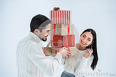 portrait of smiling multicultural couple looking at each other while holding stack of wrapped christmas gifts Stock Photo