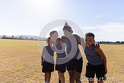 Portrait of smiling multiracial elementary boys standing with arm around on school soccer field Stock Photo