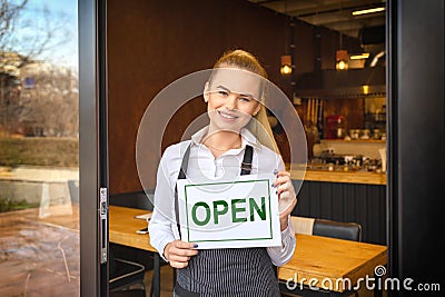 Portrait of smiling owner standing at restaurant door holding open sign, small family business Stock Photo