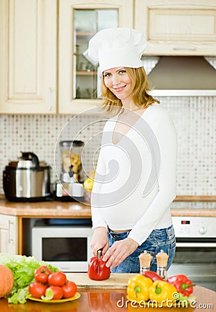 Portrait of a smiling pregnant woman cooking in her kitchen Stock Photo