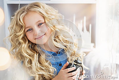 Portrait of smiling pretty little girl with a clock at hands near the window Stock Photo