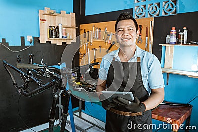 Portrait of smiling a repairman in an apron as work clothes using a pad Stock Photo