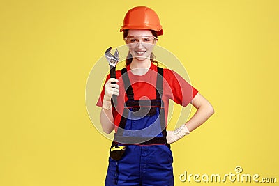 Builder woman holding adjustable wrench, looking at camera with happy facial expression. Stock Photo